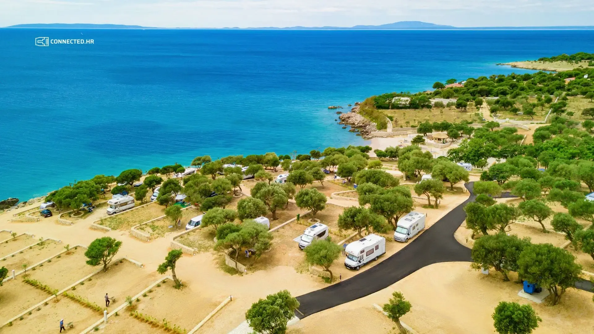 Kamp s kamp-kućicama među maslinama uz more, snimljen iz zraka